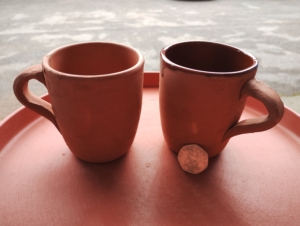 Photo of glazed and unglazed terracotta mugs sat on a platter